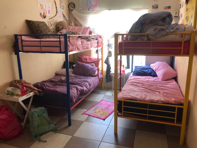 Zwei Hochbetten aus Eisengestellen und ein paar persönliche Dinge stehen in einem kleinen Kinderzimmer.